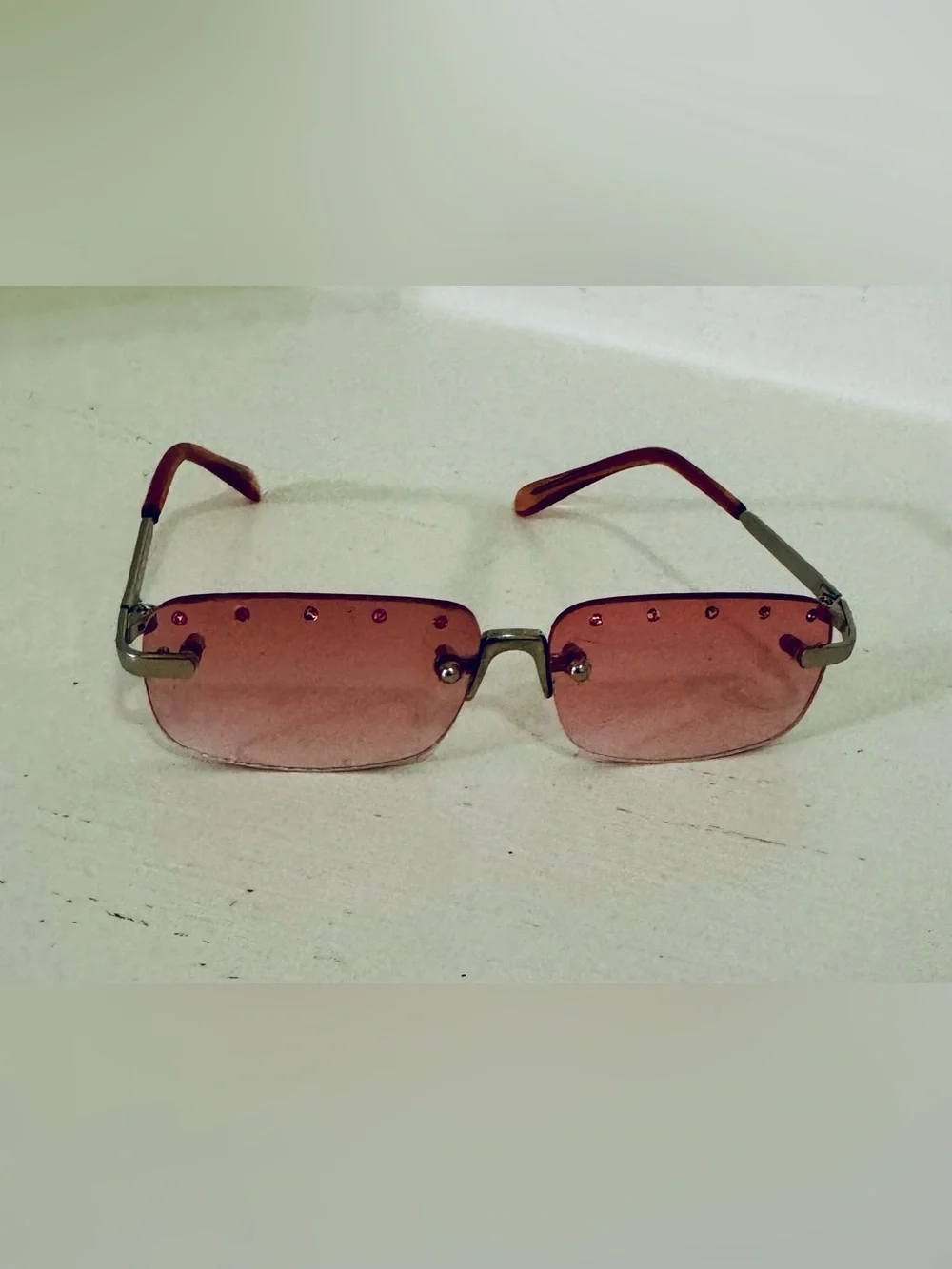 Stylish pink rimless sunglasses adorned with decorative rhinestones. These glass